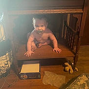 Jase Jr. joined the competition — help win amazing prizes! baby, child, pacifier, wooden_furniture, sitting, shelf, indoor, floor, toy, box, curious, person, home, wood, clutter, crawling, face, hand, foot, dim_lighting