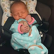 Athena is registered to the contest to win money with this photo: newborn, baby, infant, sleeping, car_seat, blanket, swaddle, clothing, pink, blue, polka_dots, pillow, head, face, hand, fist, portrait, indoors, cozy, child