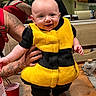 Rowen joined the competition — help win amazing prizes! baby, child, costume, bee_costume, smiling, tattoo, arm, kitchen, table, red_cup, notification, phone_screen, person, indoor, light, face, holding, clothing, happy, cute