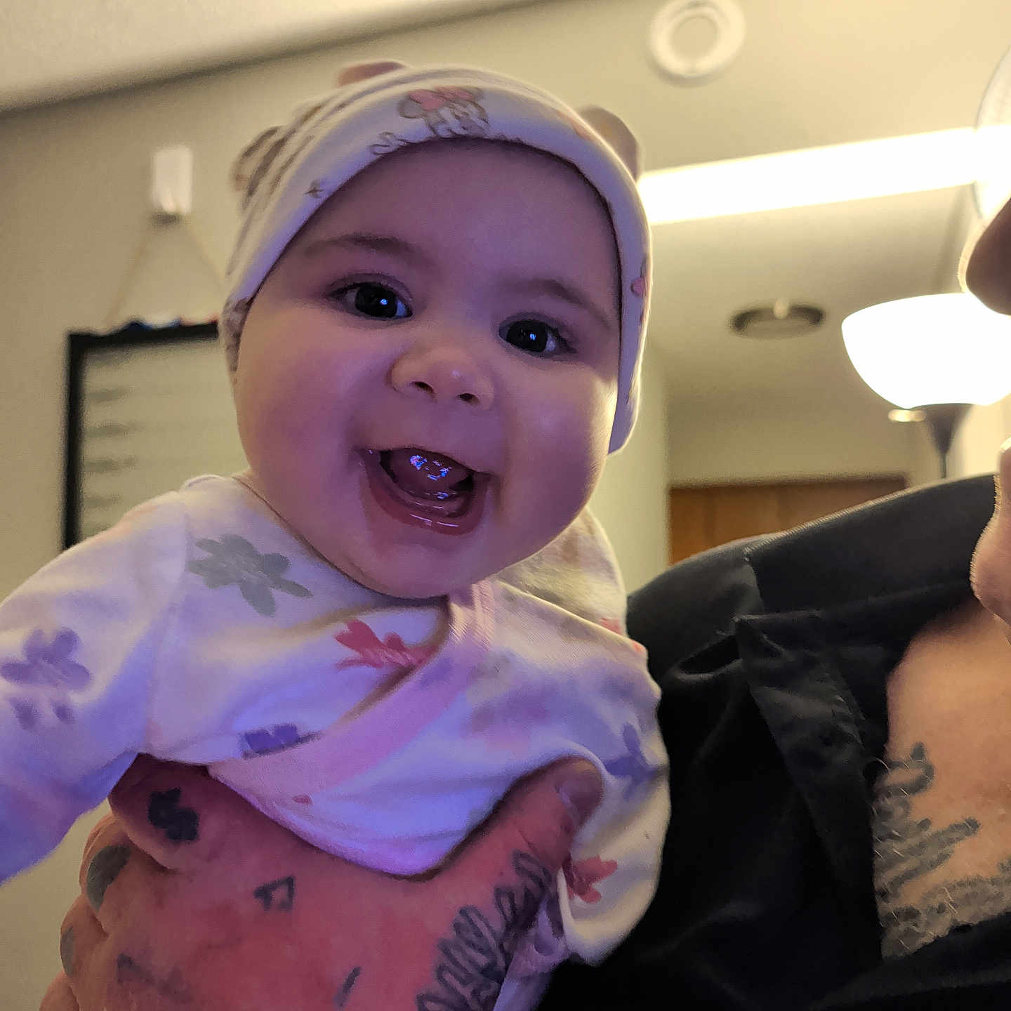 Aiyah is registered to the contest to win money with this photo: adult, baby, background, ceiling, child, clothing, cute, face, hand, happy, hat, holding, indoor, infant, lamp, person, portrait, room, smiling, tattoo