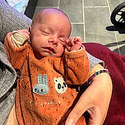 Elijah participe au concours pour gagner de l'argent avec cette photo : animal_patches, arm, baby, clothing, cozy, cute, floor, hands, holding, human, indoor, newborn, onesie, orange, peaceful, person, resting, sleeping, soft_lighting, tiled_floor