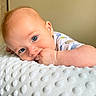 Dylan joined the competition — help win amazing prizes! baby, infant, child, portrait, blue_eyes, lying_down, smiling, curious, hand, fist, chewing, blanket, white_blanket, soft_texture, onesie, bedroom, indoor, close_up, face, photography