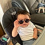 baby, child, sunglasses, high_chair, white_shirt, gray_pants, hand_gesture, indoor, living_room, couch, person, cute, fashion, seated, young_child, furniture, cosco_kids, portrait, funny, casual