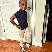 Kalanni joined the competition — help win amazing prizes! child, girl, pink_bow, black_shirt, beige_pants, sneakers, wood_floor, door, indoor, pose, smile, fashion, casual, hair, face, person, standing, confident, young, portrait