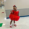child, cute, fashion, floor_tiles, girl, happy, indoor, peace_sign, person, portrait, pose, posing, red_bow, red_dress, school_hallway, shoes, smile, socks, white_wall, young