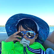 Emiliano joined the competition — help win amazing prizes! baby, blue, boat, child, green, hair, hand, lake, neon_clothing, outdoor, pacifier, portrait, seated, smiling, sun_hat, sunglasses, sunny, toddler, vacation, water