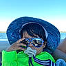 baby, blue, boat, child, green, hair, hand, lake, neon_clothing, outdoor, pacifier, portrait, seated, smiling, sun_hat, sunglasses, sunny, toddler, vacation, water