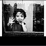 child, toddler, black_and_white, window, reflection, smile, hand, face, curly_hair, urban, buildings, glass, portrait, greeting, young_child, monochrome, cute, happy, indoors, casual