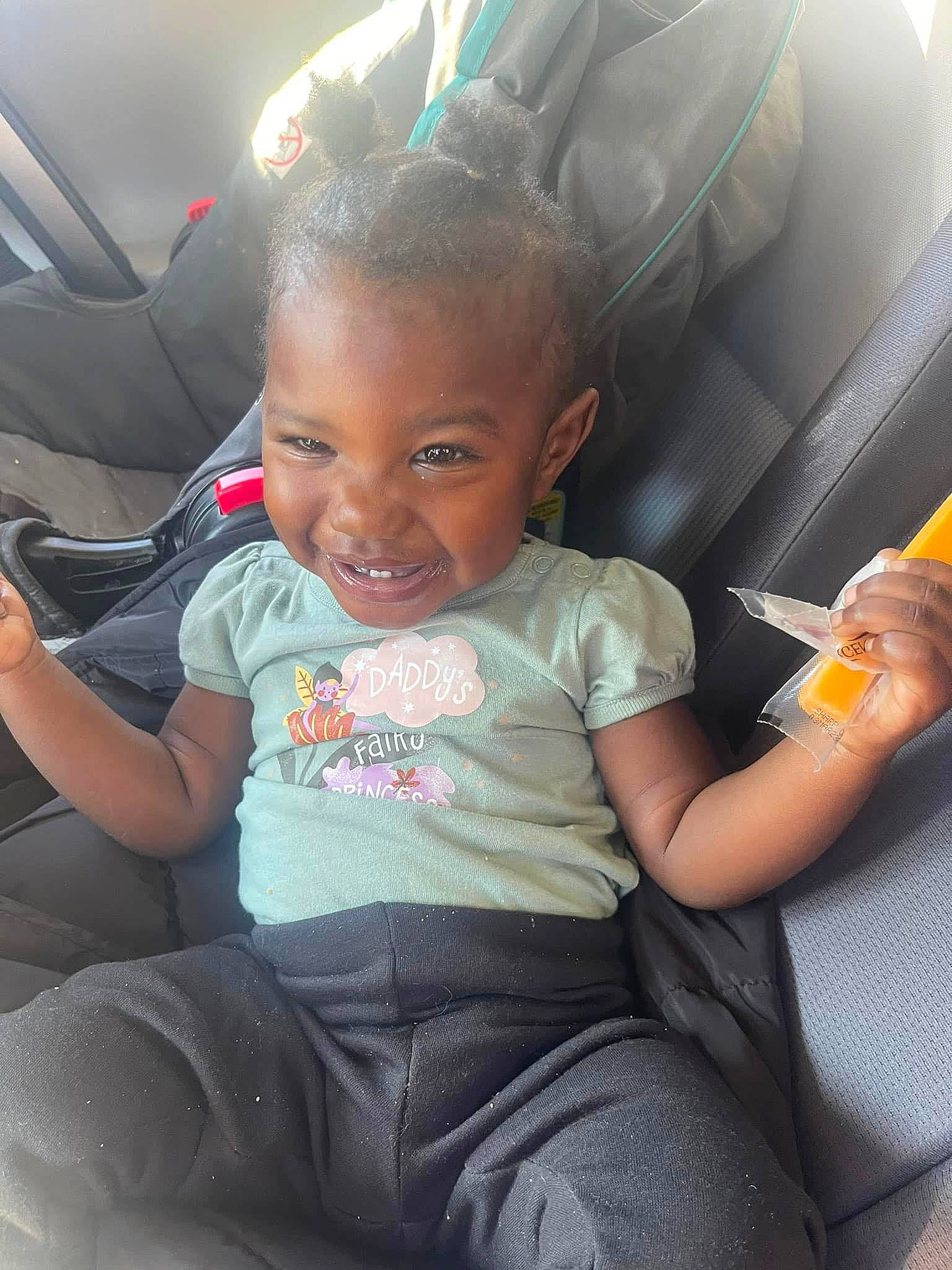 Melody is registered to the contest to win money with this photo: baby_toddler_clothing, car, car_seat, comfort, cool, facial_expression, finger, fun, happy, joy, lap, leg, motor_vehicle, mouth, person, skin, smile, steering_wheel, summer, toddler