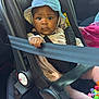 baby, car_seat, seat_belt, hat, blue_hat, infant, child, car_interior, toy, pink_blanket, clothing, sitting, straps, safety, portrait, young_child, serious_expression, indoor, person, cute