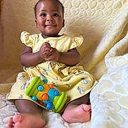 Missy K is registered to the contest to win money with this photo: baby, child, yellow_dress, toy, colorful_toy, smile, happy, clapping_hands, barefoot, blanket, heart_pattern, sitting, cute, indoors, portrait, infant, soft_lighting, playful, comfort, bunny_prints