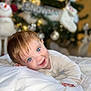 toddler, baby, blue_eyes, smiling, white_blanket, christmas_tree, holiday, snowman, indoors, cute, portrait, child, soft_lighting, festive, cozy, happy, infant, face, expression, warm