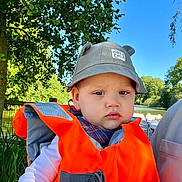 Maël participe au concours pour gagner de l'argent avec cette photo : baby, bag, baseballcap, cap, clothing, coat, face, grass, hat, head, jacket, lifejacket, outdoors, person, photography, plant, portrait, tree, vegetation, vest
