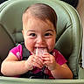 baby, child, high_chair, popsicle, smiling, happy, indoor, face, hands, food, cute, young_child, seat, clothing, pink_shirt, skin, hair, table, infant, playful