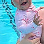 baby, child, smiling, swimsuit, flamingo_pattern, water, pool, adult_hand, happy, wet_hair, skin, outdoor, summer, playful, splash, cute, person, holding, young_child, fun