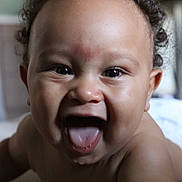 Nayan participe au concours pour gagner de l'argent avec cette photo : baby, child, curly_hair, smiling, tongue_out, close_up, face, skin, happy, infant, mouth_open, indoor, person, young_child, expression, cute, portrait, cheerful, playful, head