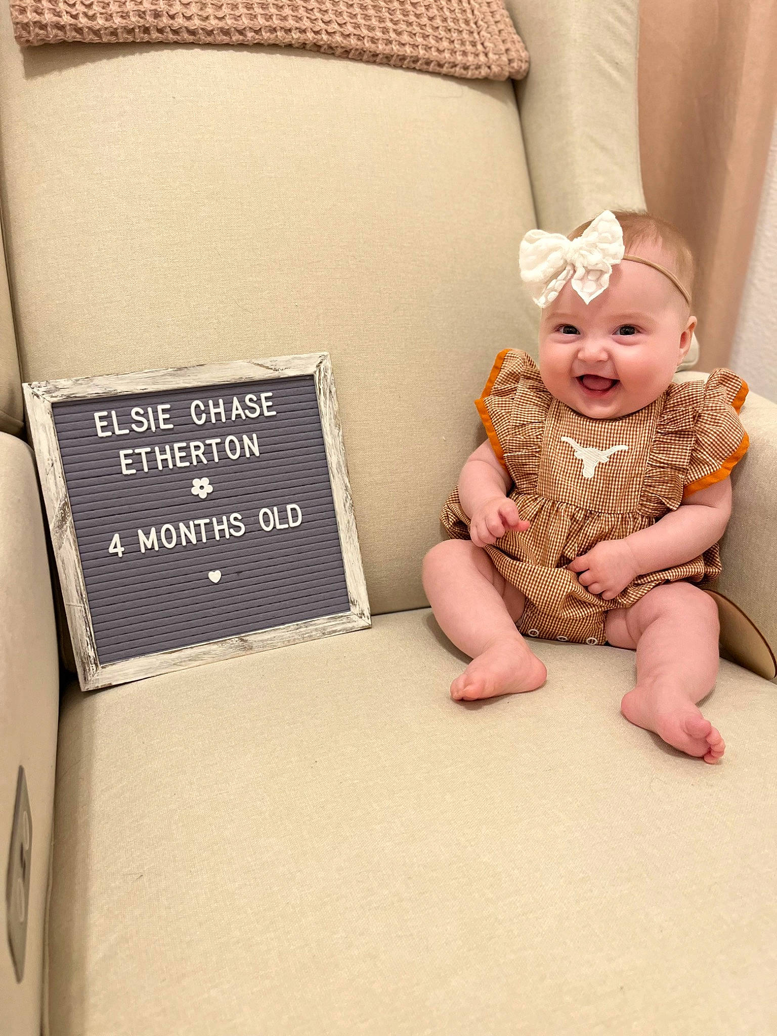 Elsie is registered to the contest to win money with this photo: baby, baby_toddler_clothing, child, comfort, flooring, font, foot, happy, headwear, linens, paper_product, pattern, peach, person, portrait_photography, rectangle, room, sitting, sleeve, smile