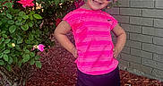 Tatym is registered to the contest to win money with this photo: black_shorts, blonde_hair, brick_wall, casual_clothing, child, flowers, girl, green_leaves, hair_tie, happy, mulch, nature, outdoor, pink_shirt, pink_shoes, posing, rose_bush, smile, sunglasses, sunny