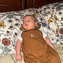 Mateo joined the competition — help win amazing prizes! baby, infant, newborn, sleeping_baby, overalls, brown_overalls, onesie, pillow, floral_pillow, bed, headboard, blanket, face, hand, peaceful, indoors, carhartt_logo, portrait, clothing, nursery