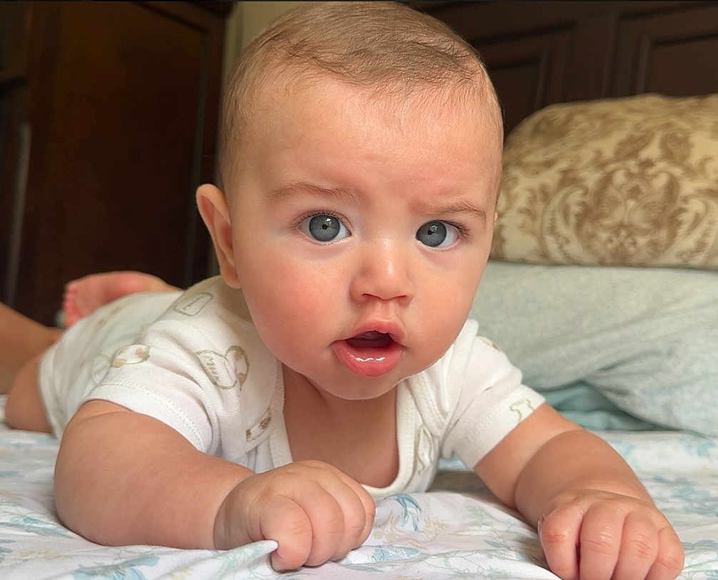 Jacob Rojas is registered to the contest to win money with this photo: baby, infant, child, blue_eyes, lying_down, bed, pillow, white_clothing, indoor, curious_expression, close_up, skin, hand, face, head, young_child, mouth_open, furniture, blanket, portrait