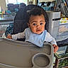 baby, baby_gear, bib, child, couch, curious, feeding, food, furniture, high_chair, home, indoor, living_room, messy_face, person, plate, portrait, table, toddler, window