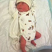 Noah participe au concours pour gagner de l'argent avec cette photo : baby, newborn, infant, hospital, blanket, hat, onesie, diaper, crib, swaddle, sleeping, peaceful, healthcare, nursery, tiny_feet, skin, person, patterned_clothing, medical_id_band, laying_down