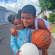 Aaliyah is registered to the contest to win money with this photo: child, children, boy, girl, smiling, basketball, volleyball, sports, outdoor, street, happy, play, summer, casual_clothing, tree, sky, clouds, house, neighborhood, friendship