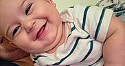 Jasper is registered to the contest to win money with this photo: arm, baby, cheeks, child, closeup, cute, expression, face, hand, happy, human, indoor, infant, joy, person, portrait, skin, smile, striped_shirt, young
