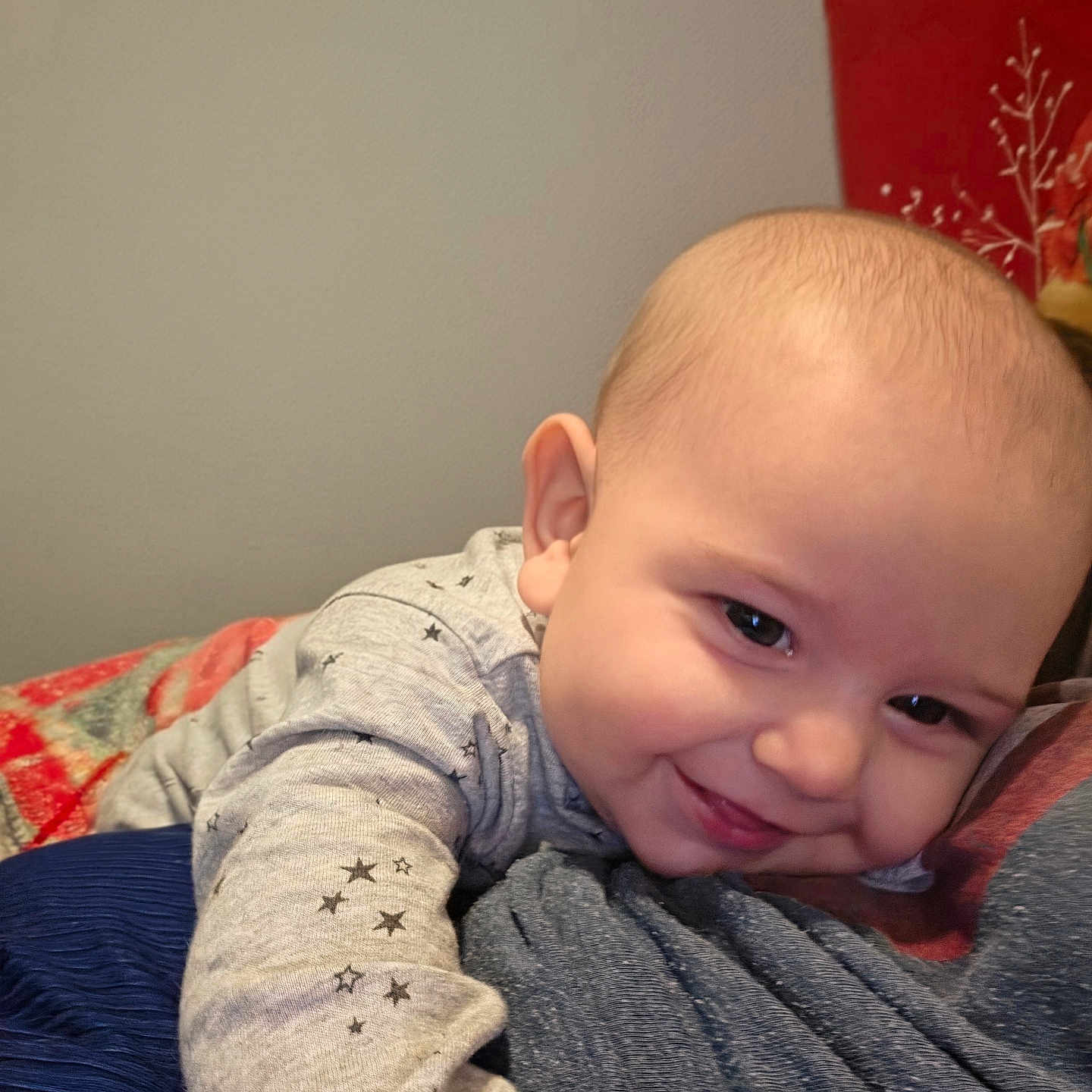 Jasper joined the competition — help win amazing prizes! baby, smile, face, child, pajamas, stars, cozy, blanket, lying_down, person, skin, head, cute, happy, indoor, infant, closeup, portrait, warm, comfort