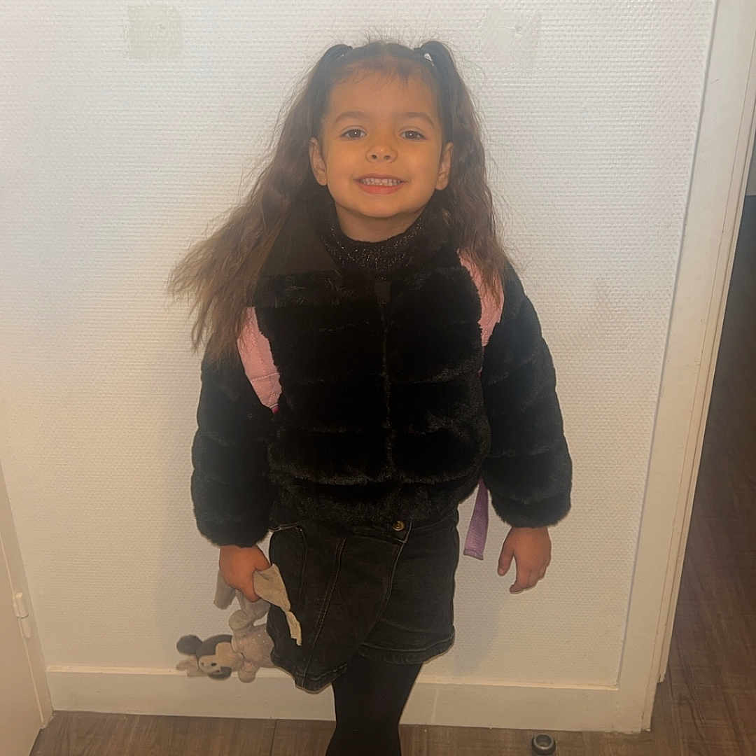 Shayana a rejoint le concours — aidez-le/la à gagner de superbes lots ! black_jacket, boots, casual, child, fashion, floor, girl, happy, holding, indoor, person, pigtails, plush_toy, portrait, skirt, smiling, standing, wall, wooden_floor, young