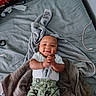 Jaiden is registered to the contest to win money with this photo: baby, smiling, towel, blanket, bed, clothing, pants, onesie, dollar_bill_print, infant, happy, hands_clasped, indoor, person, cute, lying_down, fabric, head, skin, child