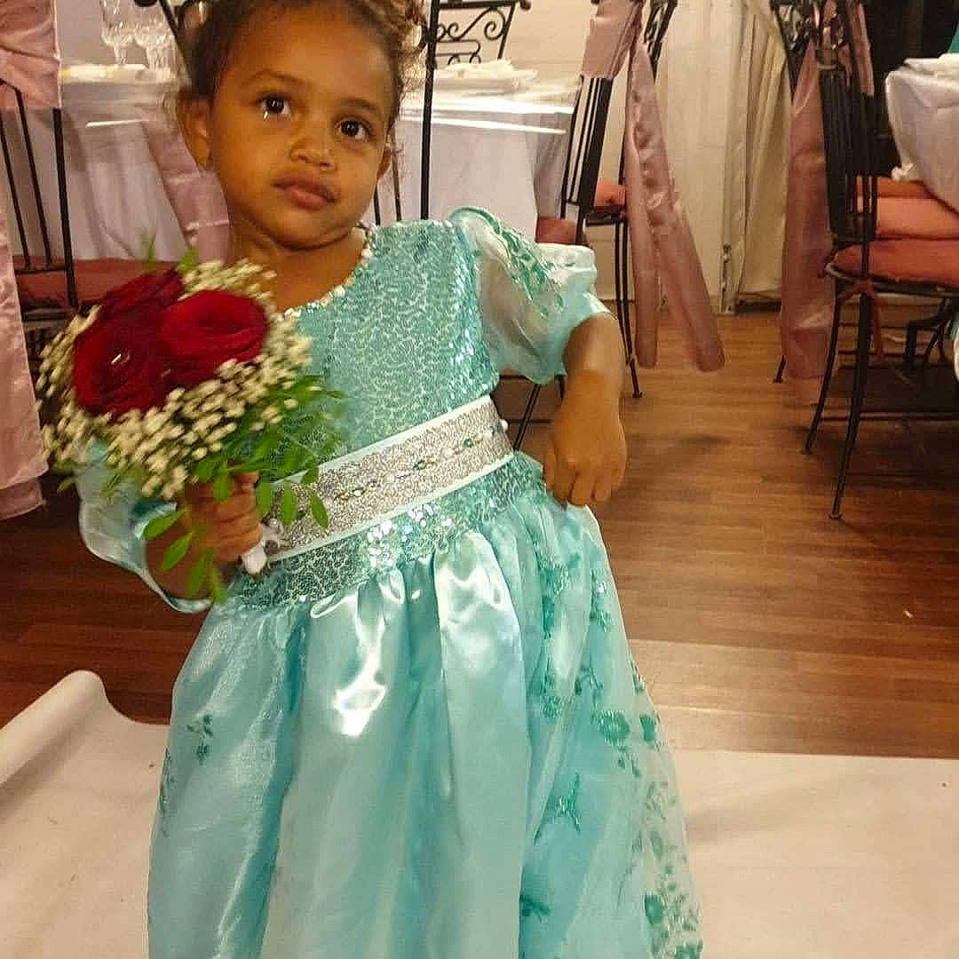 Assiya participe au concours pour gagner de l'argent avec cette photo : bridal_party_dress, ceremony, child, clothing, costume, dress, event, fashion_design, floral_design, floristry, flower, formal_wear, gown, green, person, plant, shoulder, smile, textile, tradition