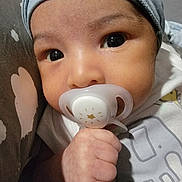 Eythan is registered to the contest to win money with this photo: baby, pacifier, hand, face, clothing, hat, infant, closeup, cute, child, skin, portrait, young, indoors, cozy, expression, newborn, sleepwear, holding, curious