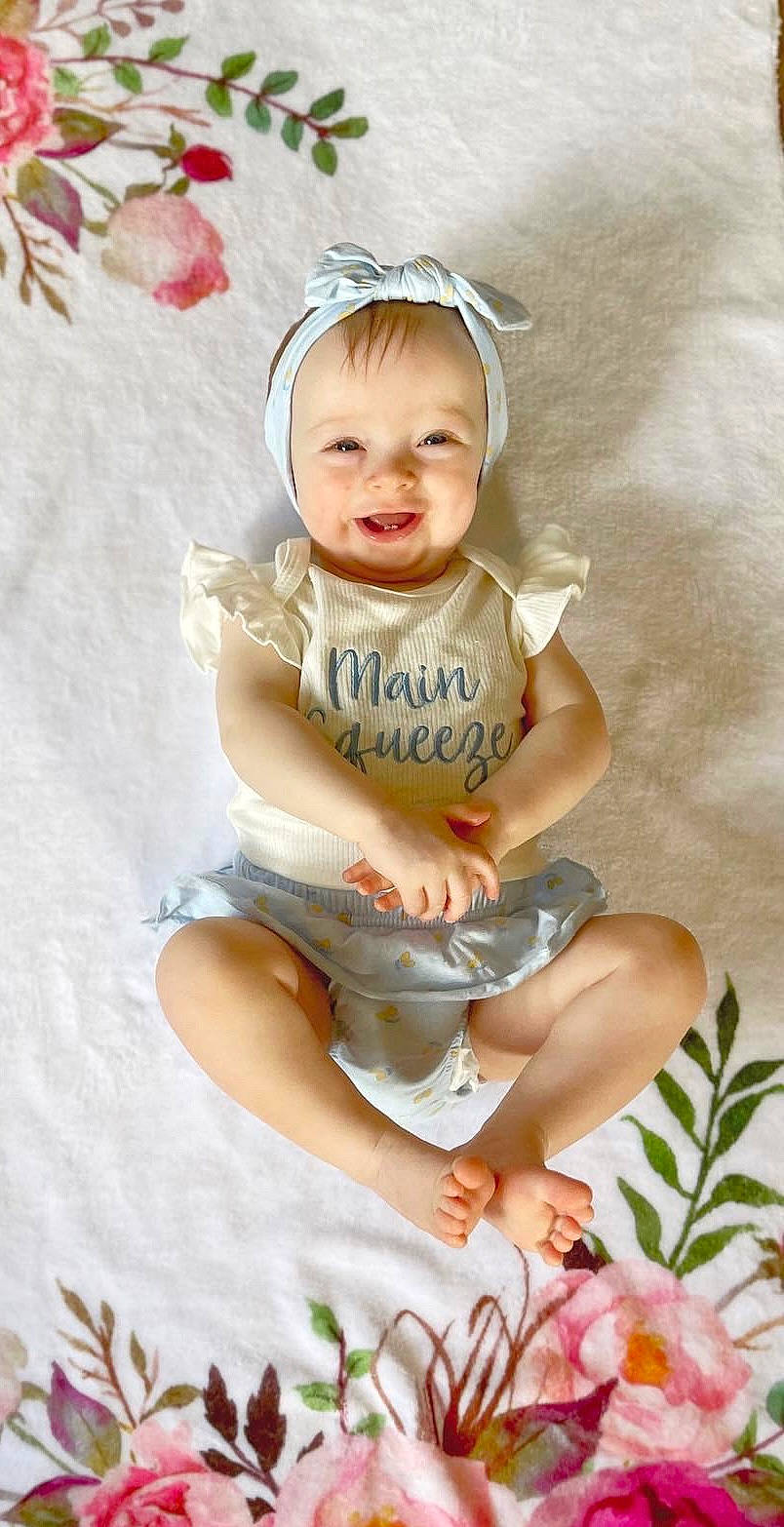 Olivia joined the competition — help win amazing prizes! baby, baby_toddler_clothing, child, comfort, face, facial_expression, fashion_accessory, happy, headband, headpiece, human_leg, pattern, person, pink, sitting, sleeve, smile, t_shirt, thigh, toddler