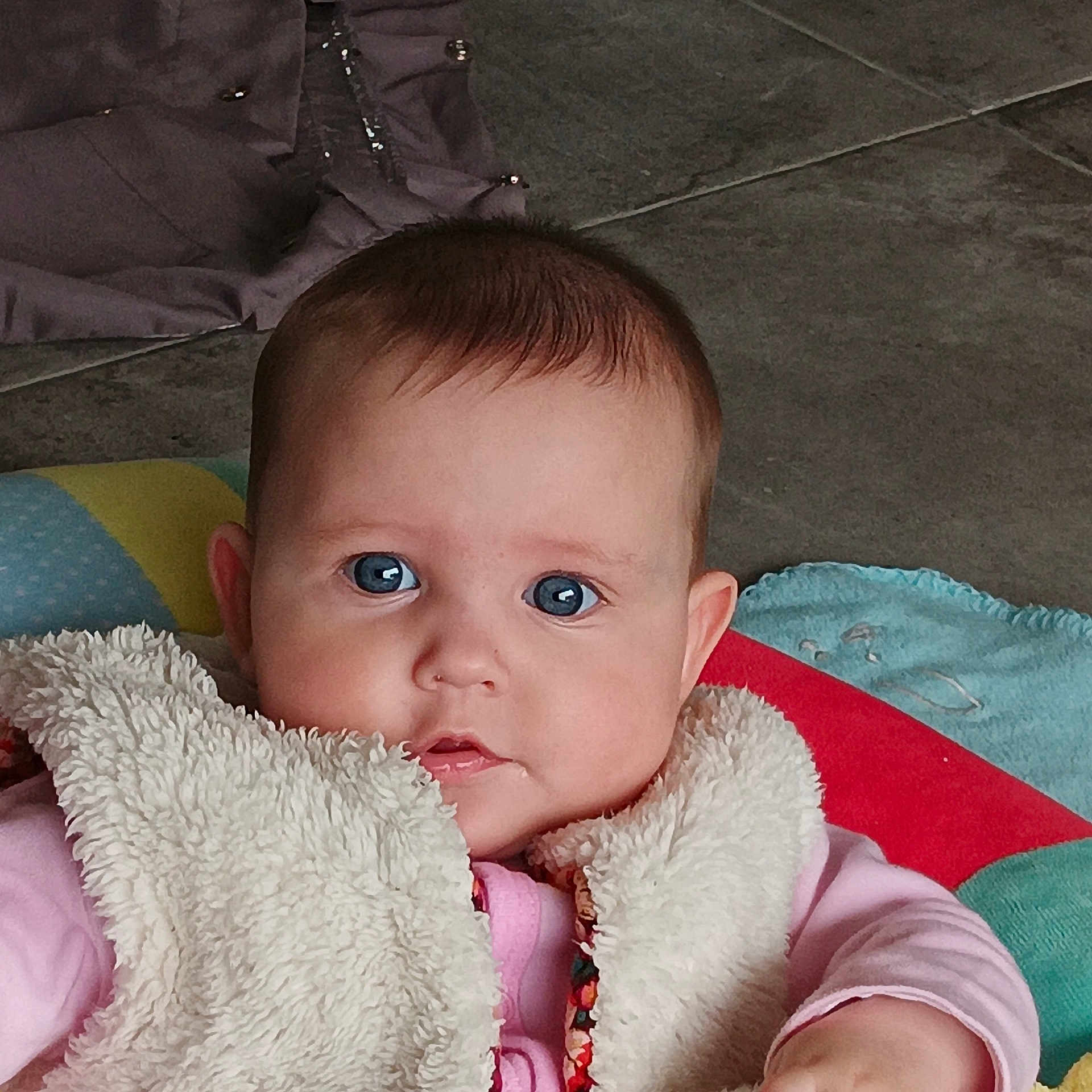 Louisy a rejoint le concours — aidez-le/la à gagner de superbes lots ! baby, blue_eyes, child, closeup, curious, cute, expression, face, floor, head, indoors, infant, person, pink_clothing, playmat, portrait, seated, soft_texture, vest, young_child