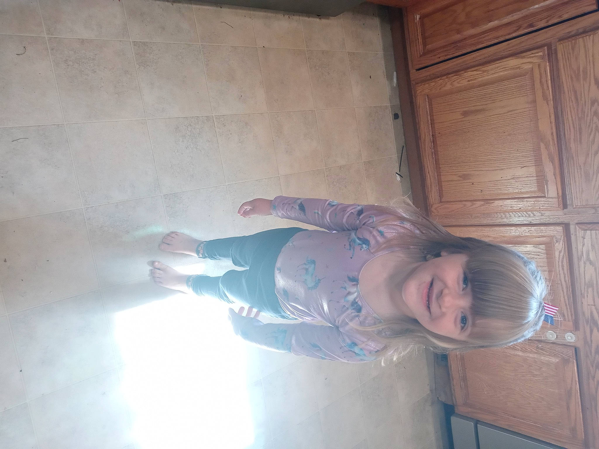 Naomi is registered to the contest to win money with this photo: arm, cabinetry, ceiling, child, door, elbow, electric_blue, floor, flooring, hardwood, human_leg, joy, leg, person, plaster, room, sitting, smile, tints_and_shades, toddler