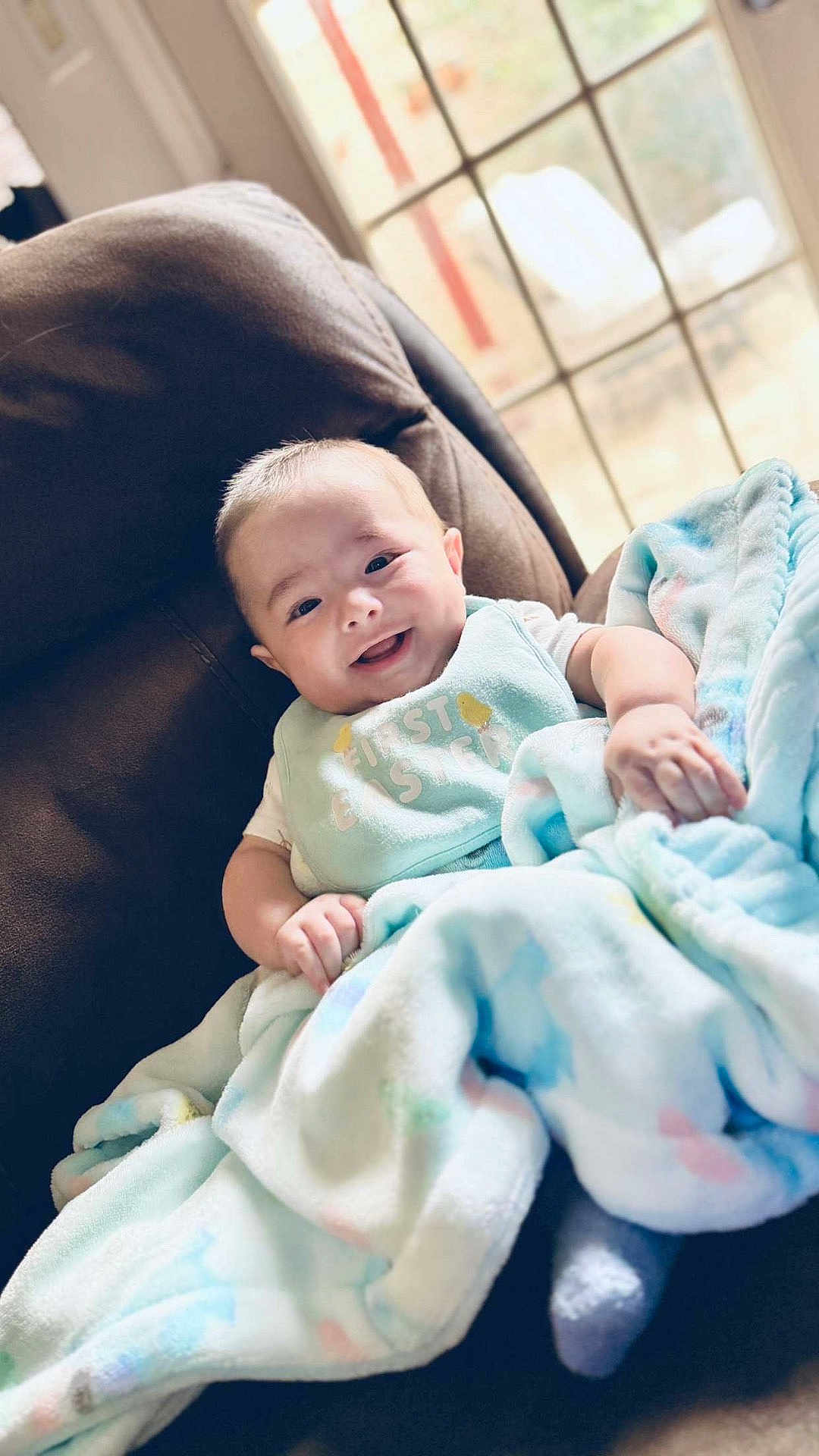 Alonso is registered to the contest to win money with this photo: baby, smiling, blanket, chair, indoors, window, happy, cozy, comfort, infant, child, soft, pastel, clothing, home, portrait, cute, relaxed, person, natural_light