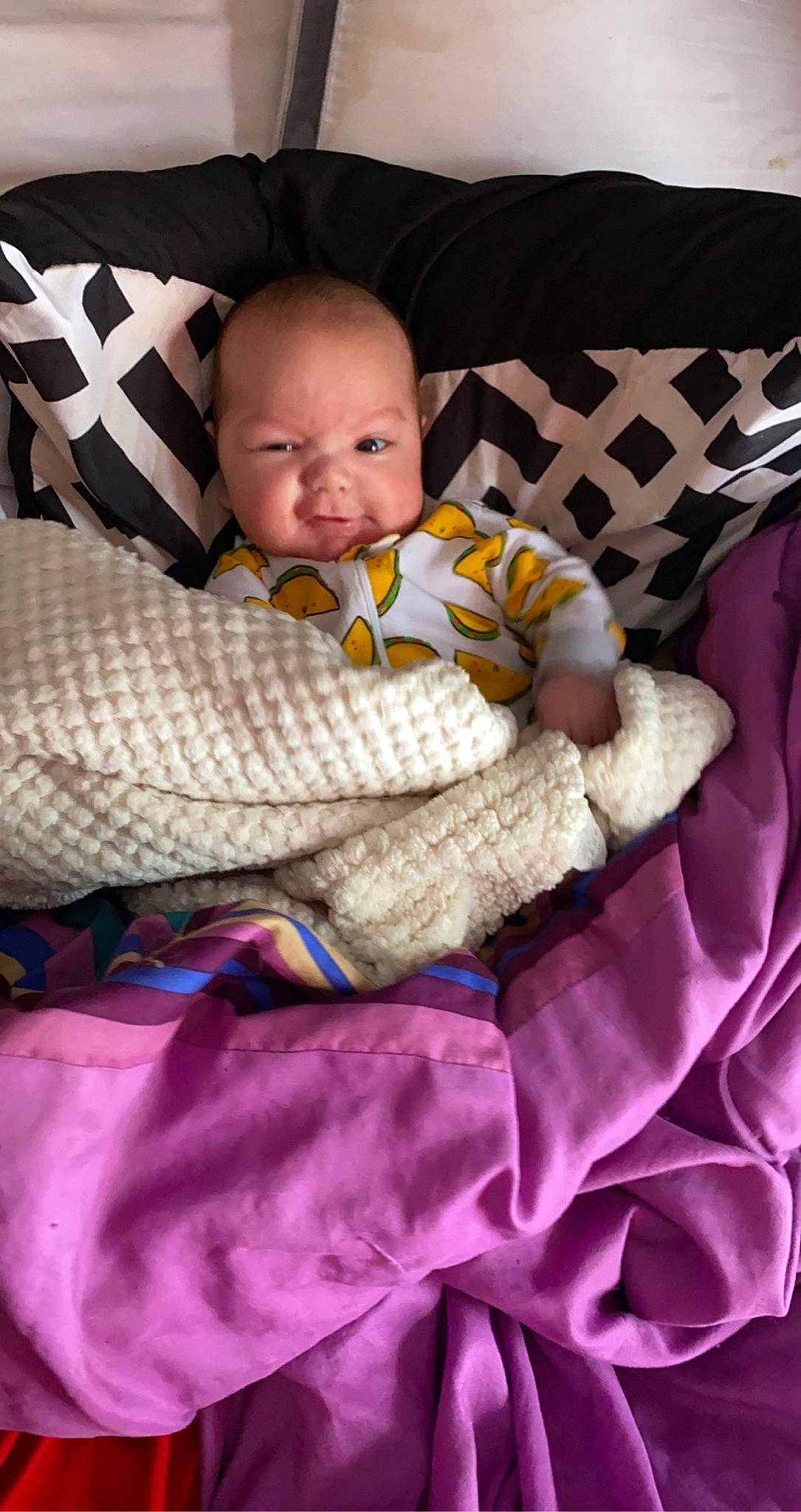 Emiliano is registered to the contest to win money with this photo: baby, baby_products, baby_toddler_clothing, bedding, child, comfort, couch, fashion_accessory, linens, magenta, pattern, person, purple, sleeve, textile, throw_pillow, toddler, white, wood, wool