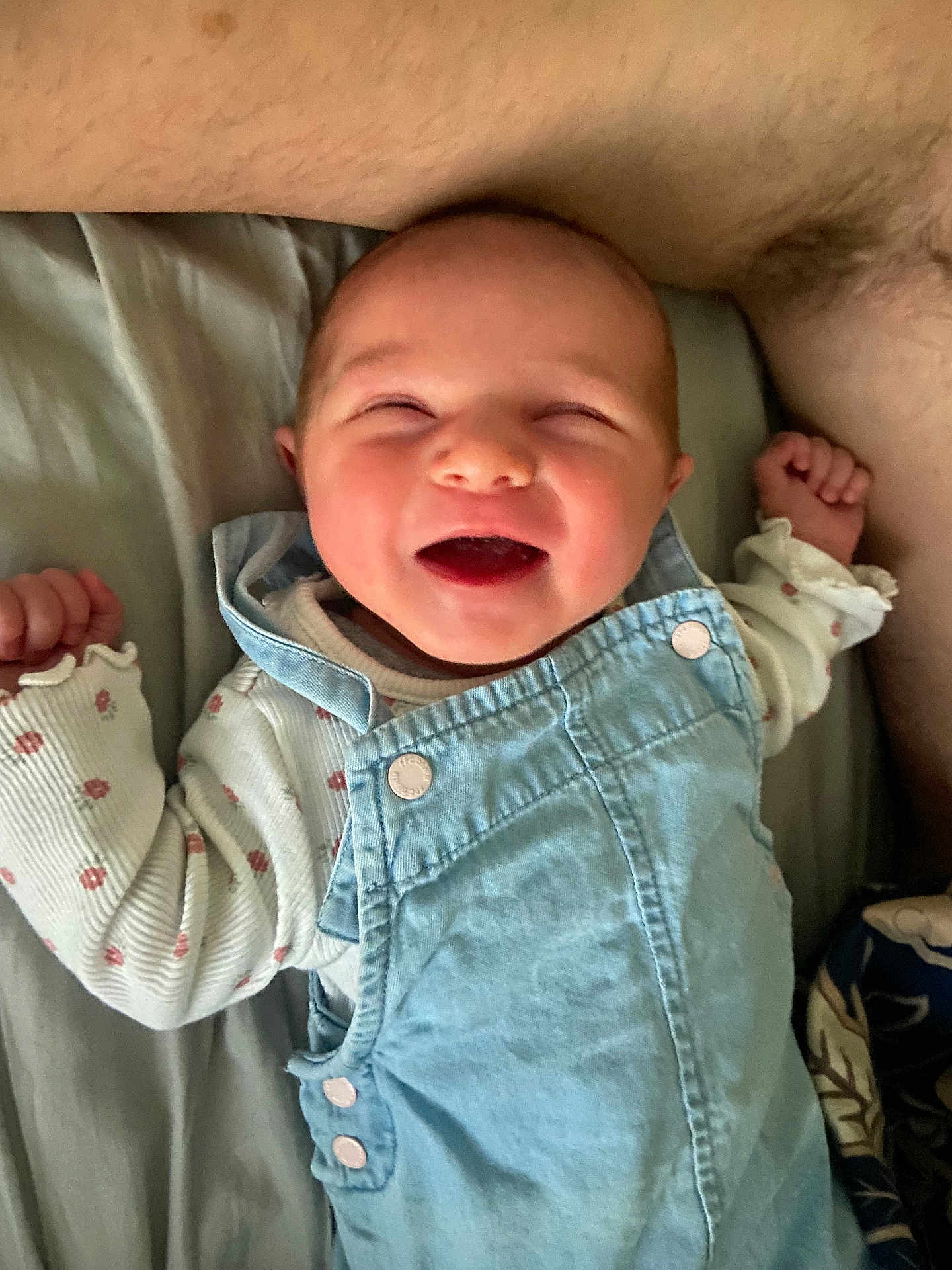 Alwena participe au concours pour gagner de l'argent avec cette photo : baby, smiling, happy, infant, denim_overalls, clothing, bed, blanket, person, cute, face, joy, sleepwear, lying_down, skin, hand, cheerful, rest, closeup, young_child