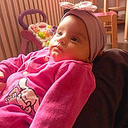 Linaya a rejoint le concours — aidez-le/la à gagner de superbes lots ! baby, bow, child, closeup, cozy, cute, face, furniture, gaze, hand, headband, indoor, infant, person, pink_clothing, portrait, soft_lighting, toy, warm_colors, wooden_chair