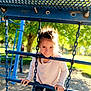 child, girl, playground, climbing, blue, bars, chains, sunlight, outdoor, park, trees, person, play, daylight, fun, young, casual_clothing, smile, happy, nature
