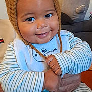 Lyvio a rejoint le concours — aidez-le/la à gagner de superbes lots ! baby, bear_ears, bib, child, cozy, cute, elephant, face, hand, happy, indoor, infant, knitted_hat, living_room, person, plush_toy, portrait, seated, smiling, striped_pajamas