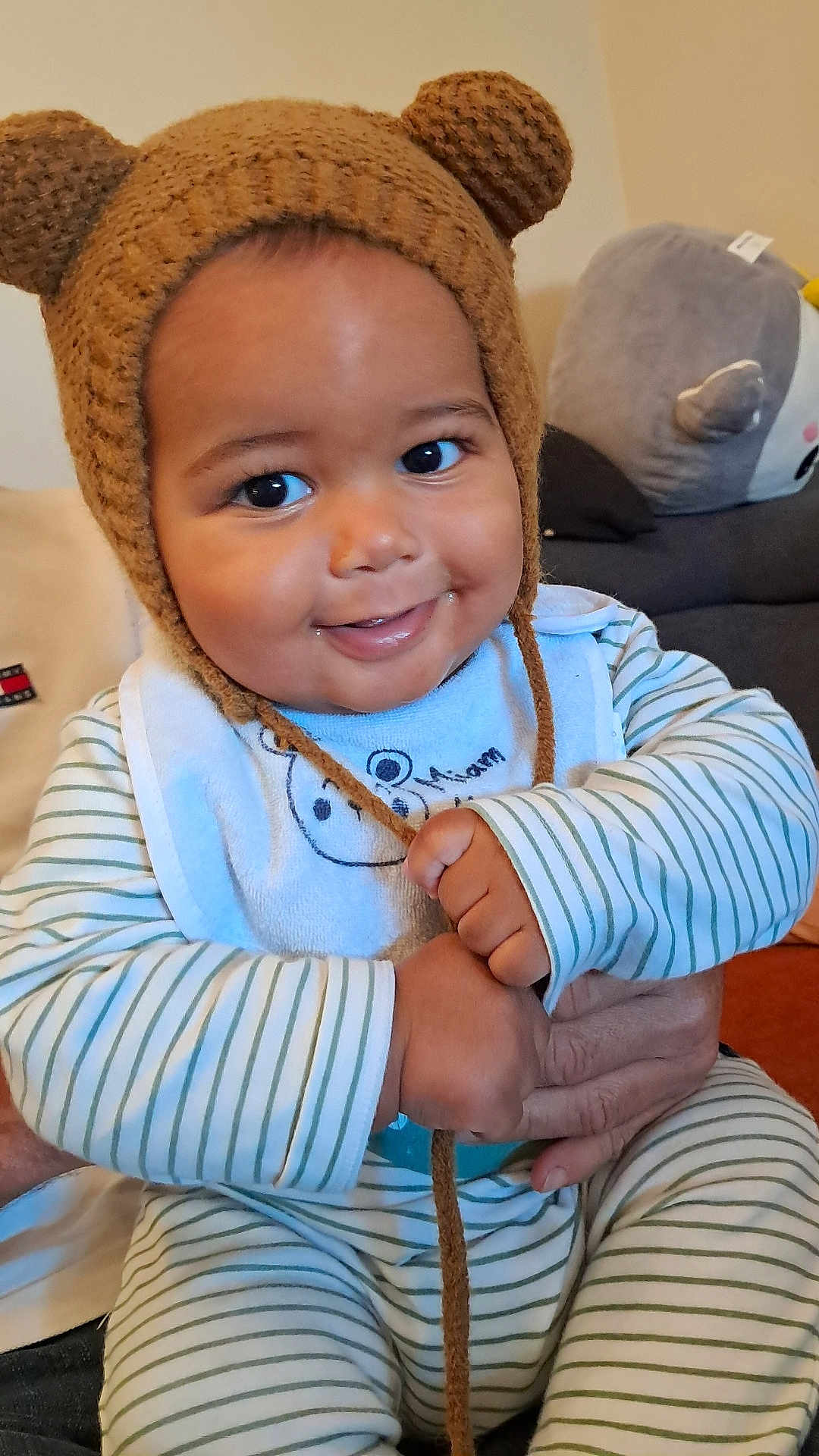 Lyvio a rejoint le concours — aidez-le/la à gagner de superbes lots ! baby, bear_ears, bib, child, cozy, cute, elephant, face, hand, happy, indoor, infant, knitted_hat, living_room, person, plush_toy, portrait, seated, smiling, striped_pajamas