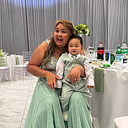 Naniko is registered to the contest to win money with this photo: bottle, celebration, chairs, child, curtain, dress, drink, event, family, flower_arrangement, happy, indoor, party, person, smile, suit, table, tie, toddler, woman