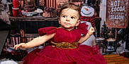 Gina a rejoint le concours — aidez-le/la à gagner de superbes lots ! toddler, child, red_dress, gold_belt, holiday, christmas, snowman, festive, indoor, bench, decorations, warm_lighting, cute, portrait, smiling, celebration, background, winter, cozy, happy