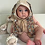 baby, child, blue_eyes, bunny_ears, hood, cute_outfit, soft_toys, teddy_bear, crocheted_toy, lion_toy, sitting, portrait, indoors, white_background, soft_lighting, infant, face, feet, expression, adorable