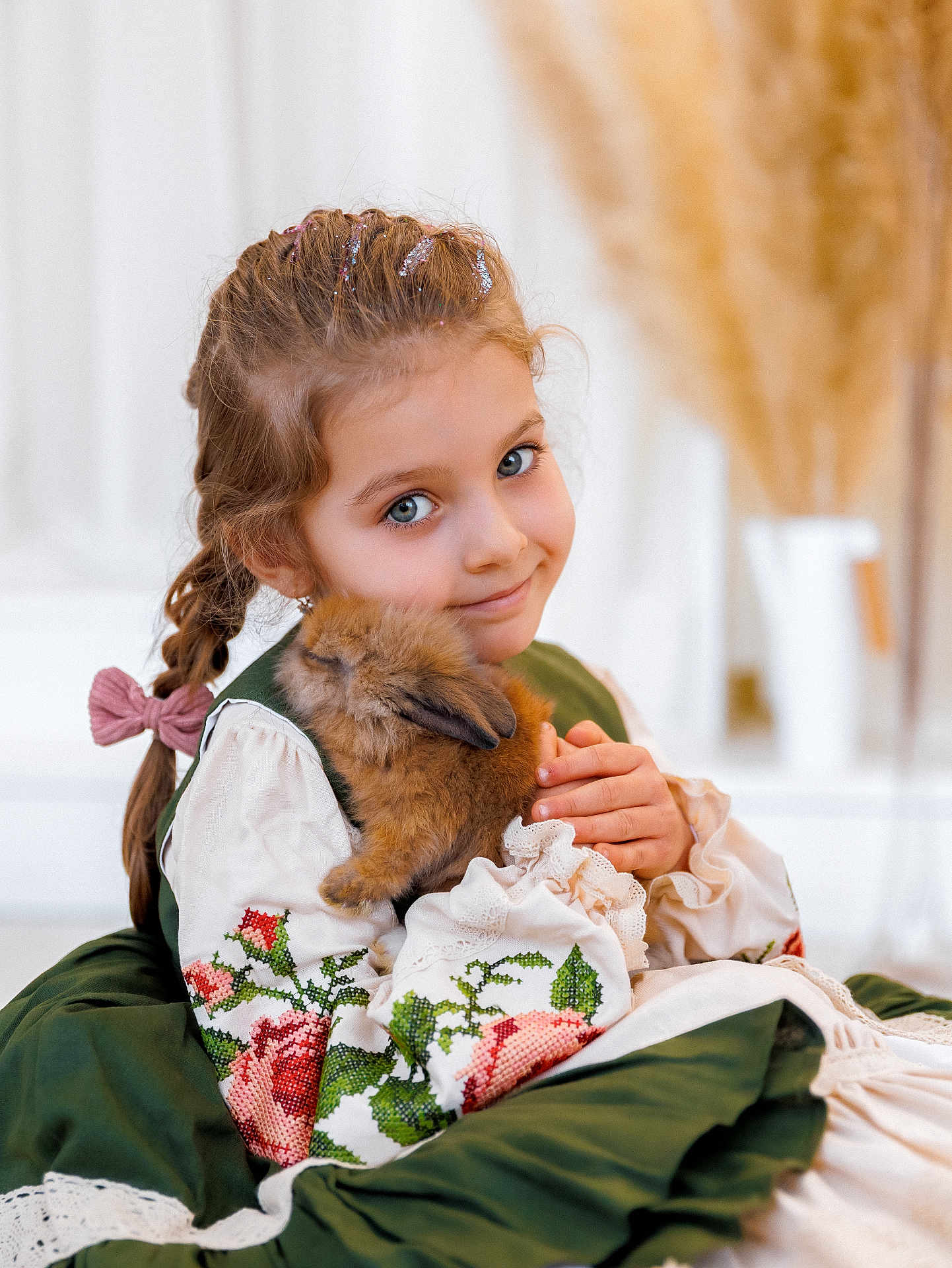 Uliana is registered to the contest to win money with this photo: child, girl, rabbit, pet, animal, cute, smile, braid, glitter, dress, embroidery, green, white, soft, cozy, indoors, portrait, holding, fluffy, adorable