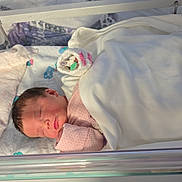 Sapphire joined the competition — help win amazing prizes! newborn, baby, sleeping, hospital, bassinet, blanket, pacifier, hat, infant, bed, healthcare, pink_clothing, rest, cute, person, child, soft_light, indoor, peaceful, wrapped