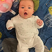 Lily-Honora participe au concours pour gagner de l'argent avec cette photo : baby, infant, onesie, blanket, plush_toy, pink, blue, glasses, bedroom, expression, mouth_open, lying_down, cute, child, soft_toy, pattern, fabric, face, hand, foot