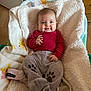 Lily-Honora participe au concours pour gagner de l'argent avec cette photo : baby, infant, smile, red_shirt, striped_clothing, grey_pants, paw_prints, blanket, soft_texture, cozy, indoor, wooden_furniture, flooring, child, cute, happy, person, portrait, clothing, warm
